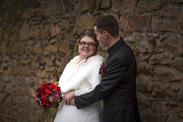 Winterhochzeit Braut und Bräutigam stehen vor Bruchsteinmauer